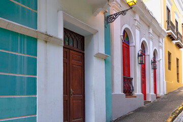 Fototapeta premium View along a sloping cobblestone street in Old San Juan Puerto Rico featuring vibrant colonial buildings with traditional wooden doors and wrought iron balconies