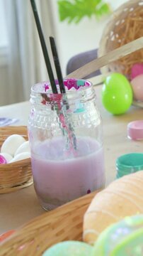 Vertical video: Panning camera showing pastel eggs and brushes in purple jar for Easter decor