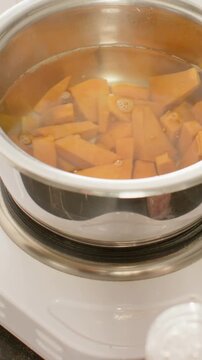 Vertical video: Heating steel pot by steamer, simmering orange wedges on counter with steam on lid