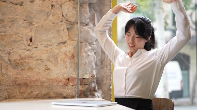 Woman rests head on desk, tired after work. She stretches arms, smiling at the sun. She looks forward, calm and refreshed. Perfect for office, wellness, or break-time scenes