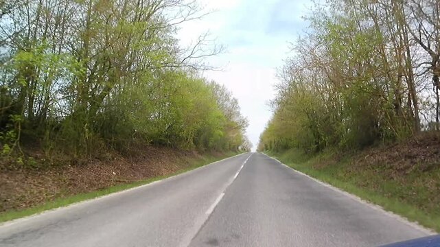Spring road ride towards a small settlement in Myjava Upland, western Slovakia, near city of Myjava. Spring broadleaf trees with fresh green foliage visible around the road