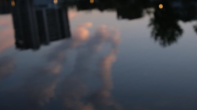 Evening clouds, buildings and tree reflections rippling on water, silent abstract background footage