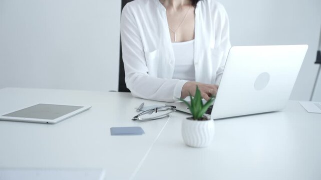 Businesswoman writing important notes on sticky paper while planning tasks on laptop, organizing workspace for efficient project management and productivity