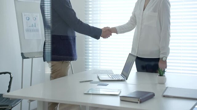 Business professionals shaking hands, establishing a deal in a modern office, confirming a successful partnership after reviewing financial data and strategy