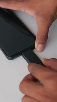 Close up of a person connecting a USB Type-C flash drive to a smartphone
