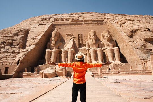Traveler standing with open arms before the Great Temple of Abu Simbel in Egypt