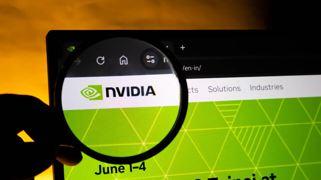 Closeup of a magnifying glass held over a computer screen showing the nvidia company website logo and branding, symbolizing technology research and analysis