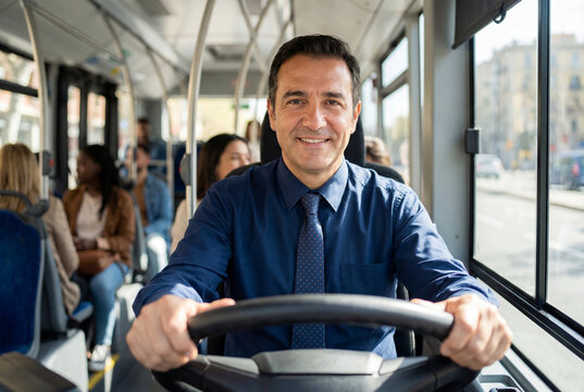 Smiling male bus driver steering city bus with passengers inside.