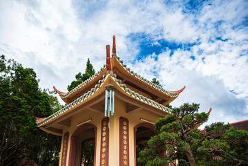 Fototapeta premium A peaceful scene featuring a traditional Vietnamese pagoda pavilion and meticulously manicured bonsai pine trees in a temple garden in Da Lat, Vietnam.