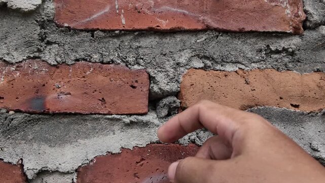 A detailed shot of an irregular brick wall layout. The video focuses on the gaps and excess mortar between the clay bricks, illustrating a raw and unpolished construction style.
