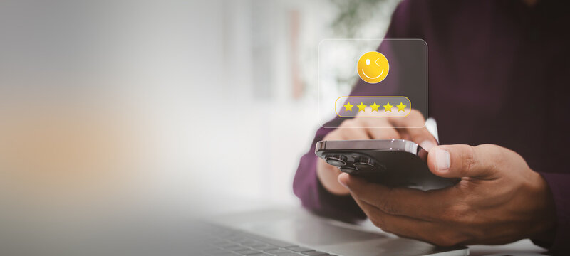 Customer satisfaction survey on smartphone with businessman giving five star rating and happy smiley face icon.