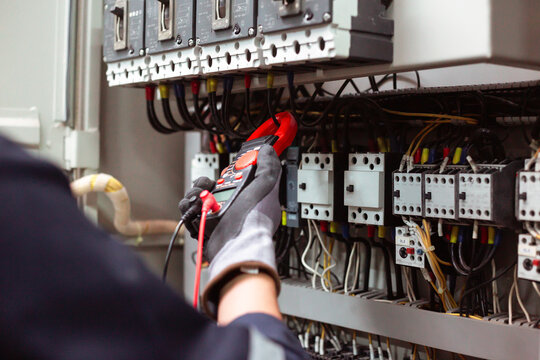 Digital multimeter testing industrial electrical circuits for maintenance.
