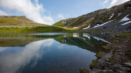 Fototapeta premium Calm reflection of rugged mountains in the turquoise waters of Summit Lake at Hatcher Pass near Wasilla Alaska United States