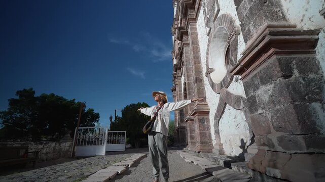 Mature woman walks and takes in the sights at Mission Church in San Ignacio Baja California Mexico under a clear blue sky