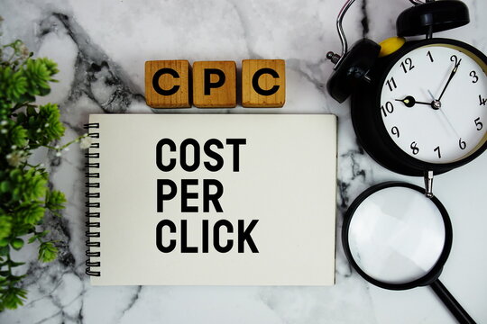 CPC Cost Per Click text with alarm clock and magnifying glass on marble background