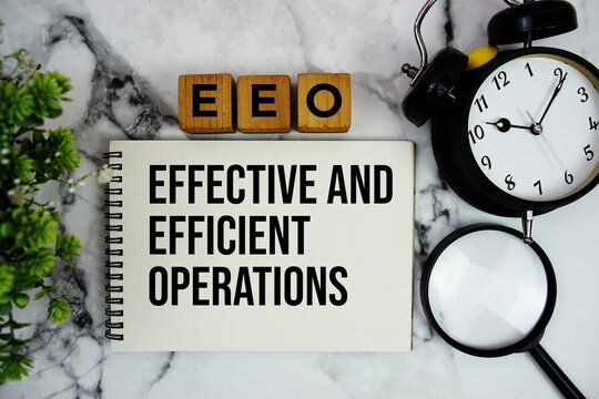 EEO Effective And Efficient Operations text with alarm clock and magnifying glass on marble background