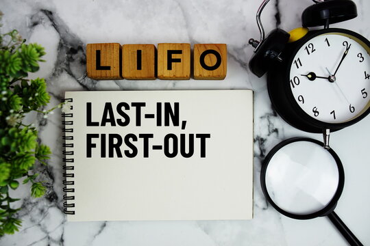 LIFO Last In, First Out text with alarm clock and magnifying glass on marble background