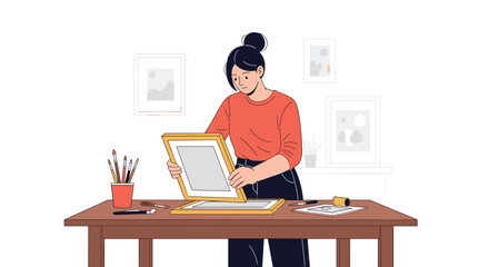 Fototapeta premium Artistic woman working at a wooden desk to frame a picture or perform screen printing in a creative studio space.