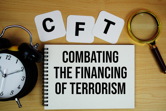 CFT Combating the Financing of Terrorism text written on notepad with magnifying glass and alarm clock on wooden background