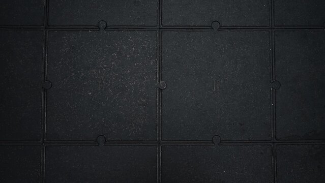Top view of black interlocking rubber floor tiles with industrial textured surface