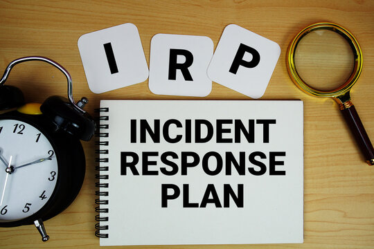 IRP  Incident Response Plan text written on notepad with magnifying glass and alarm clock on wooden background