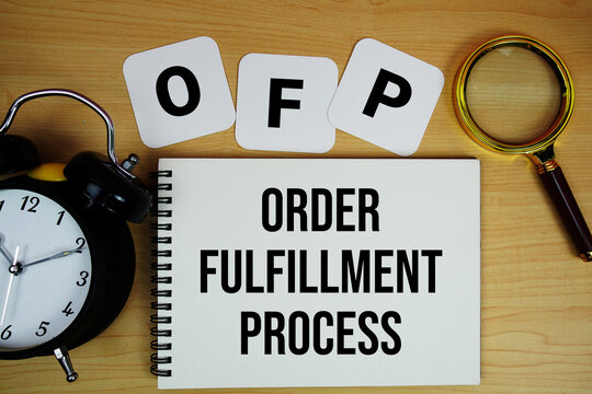 OFP Order Fulfillment Process text written on notepad with magnifying glass and alarm clock on wooden background