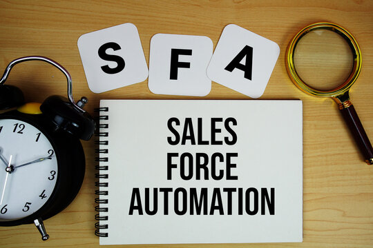 SFA Sales Force Automation text written on notepad with magnifying glass and alarm clock on wooden background
