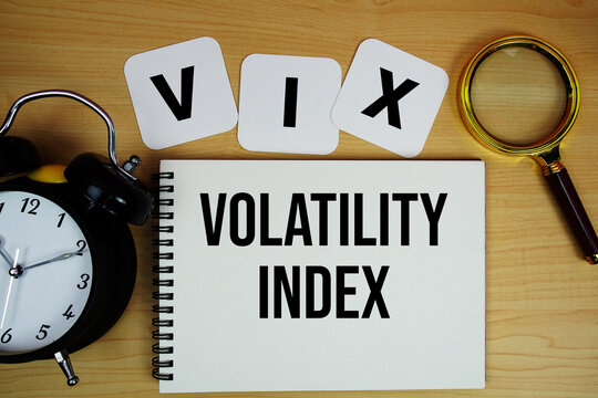 VIX Volatility index text written on notepad with magnifying glass and alarm clock on wooden background