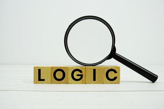 LOGIC alphabet letters with magnifying glass on wooden background