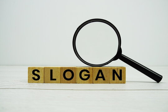 SLOGAN alphabet letters with magnifying glass on wooden background
