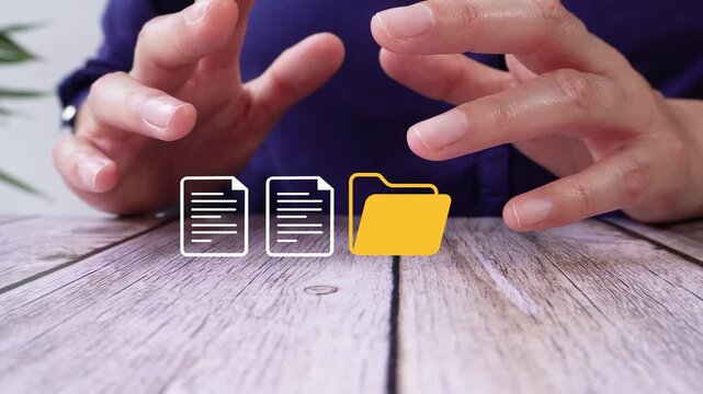 Close-up of a pair of hands on a table, protecting an animated folder icon and a couple of documents. File management.