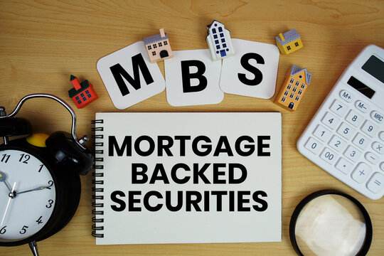 MBS Mortgage-Backed Securities text written on notepad with house model, alarm clock and magnifying glass on wooden background