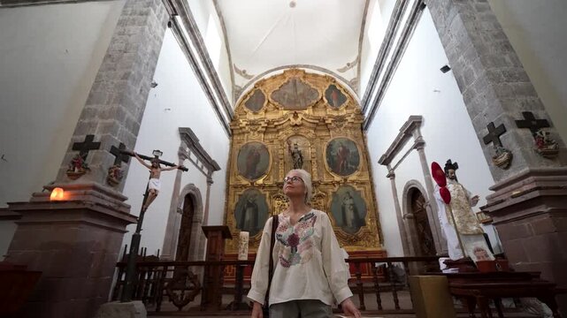 A mature woman explores Mission San Ignacio in Baja California Sur Mexico, admiring the church architecture and history inside.