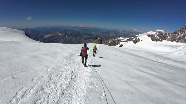 POV mountaineering in rope team with mountaineers towards summit Balmenhorn and mountain glacier panorama with Gran Paradiso in summer in Pennine Alps, Italy