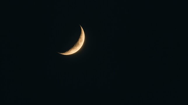 Crescent moon glowing in dark night sky, golden lunar sliver in black space, astronomical waxing moon phase background