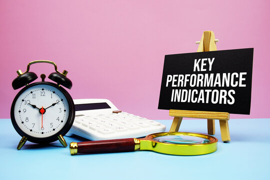 Key Performance Indicators text with calculator, alarm clock and magnifying glass on pink and blue background