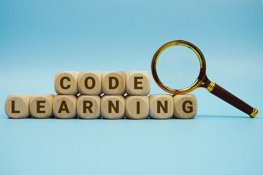 Code Learning alphabet letters wooden cube and magnifying glass on blue background