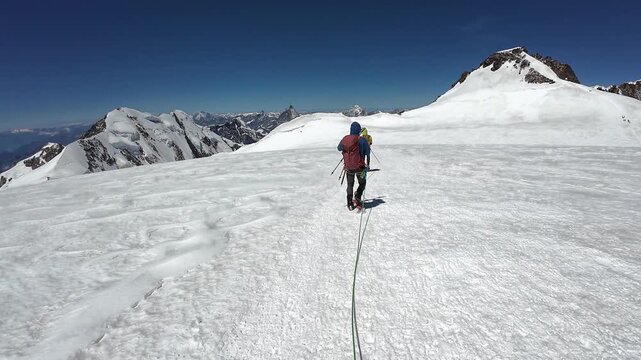 POV mountaineering in rope team with mountaineers and mountain glacier panorama with summits Lyskamm and Zumsteinspitze in summer in Pennine Alps, Switzerland