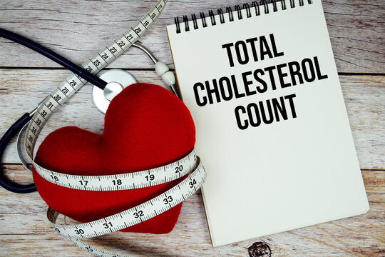 Total Cholesterol Count text with stethoscope and wrap a measuring tape around red heart on wooden background