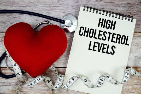 High Cholesterol Levels text with stethoscope and wrap a measuring tape around red heart on wooden background