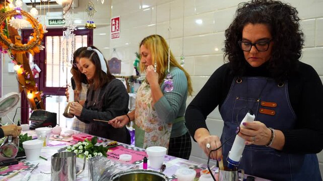 Group of female artisans creating handmade scented candles during a craft class in their workshop