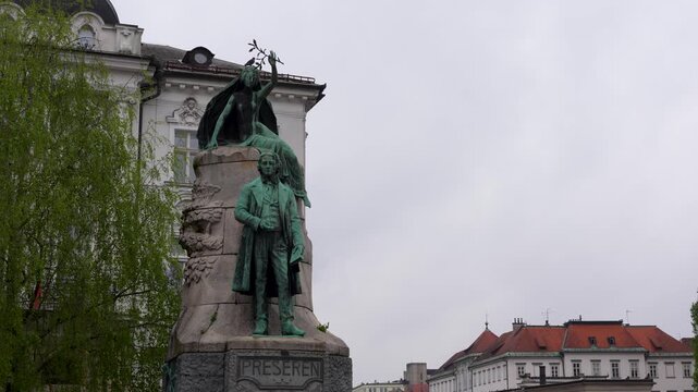 A detailed shot of the France Preseren statue in the central square of Ljubljana, Slovenia, featuring the poet and his muse against a cloudy sky.
