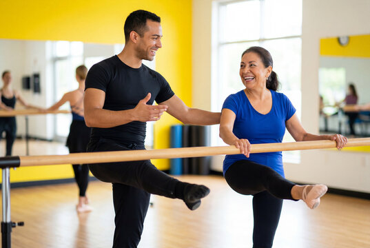 Energetic male instructor demonstrating a leg lift at a ballet barre with a cheerful senior woman