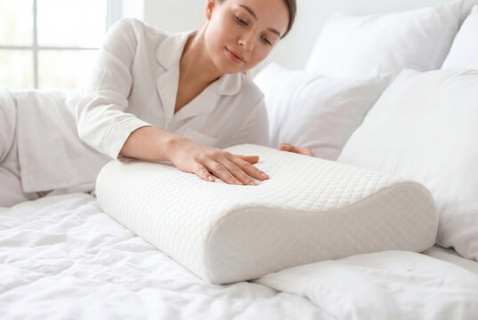 Young woman in white pajamas on a bed touching a comfortable orthopedic memory foam pillow
