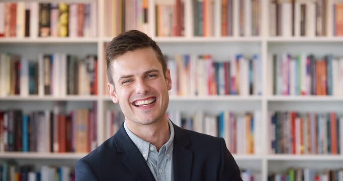 Confident, face and man in library with smile for career, knowledge and teacher job. University, professional and lecturer with opportunity, pride or happiness for college growth, literature or books