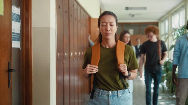 Stressed Korean female student upset over failed exam or bad grades receives emotional support from African classmate in university hallway.