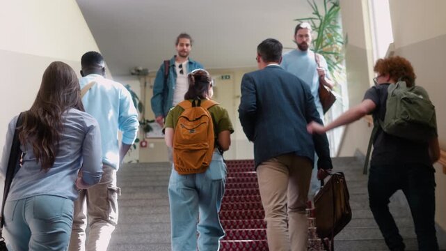 Multicultural university students and professor walking upstairs together in campus building during break between classes. Modern academic lifestyle.
