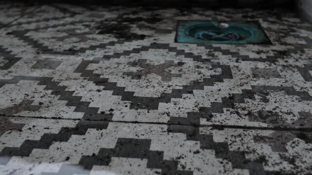 Close-up of scattered mud and black dirt residue on a patterned floor after water has receded or leaked, showing an unsanitary condition.