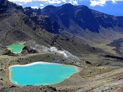 looking  down at the emerald lakes and steaming vents from red crater  on the tongariro alpine crossing  on the north island of new zealand, on a sunny summer day      



