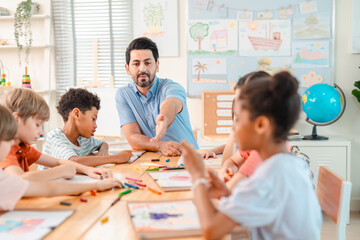 Back to school and education concept of teacher guiding children in classroom, group drawing...